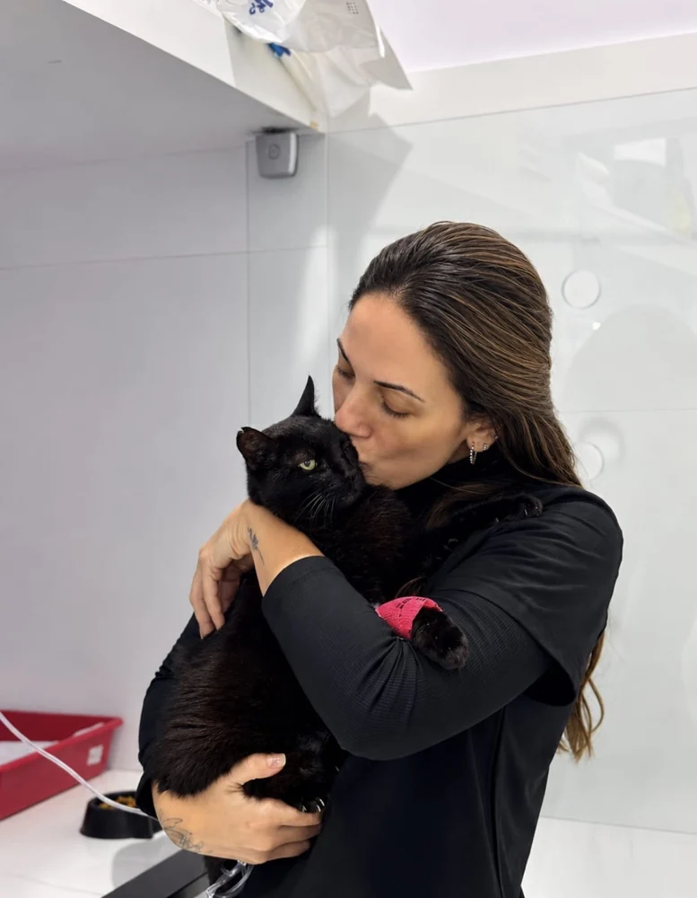 Foto real de Jeniffer Queiroz acolhendo um gato preto